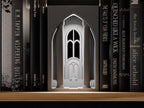 Stonecrown Hall Book Nook in a light neutral color, shown from the front between books on a wooden shelf.
