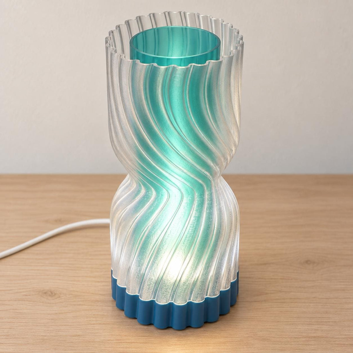Elevated view of the Lagoon Mist Rillora lamp showing its clear scalloped outer rim, Teal cylindrical inner diffuser, Marine Blue base and white cord.