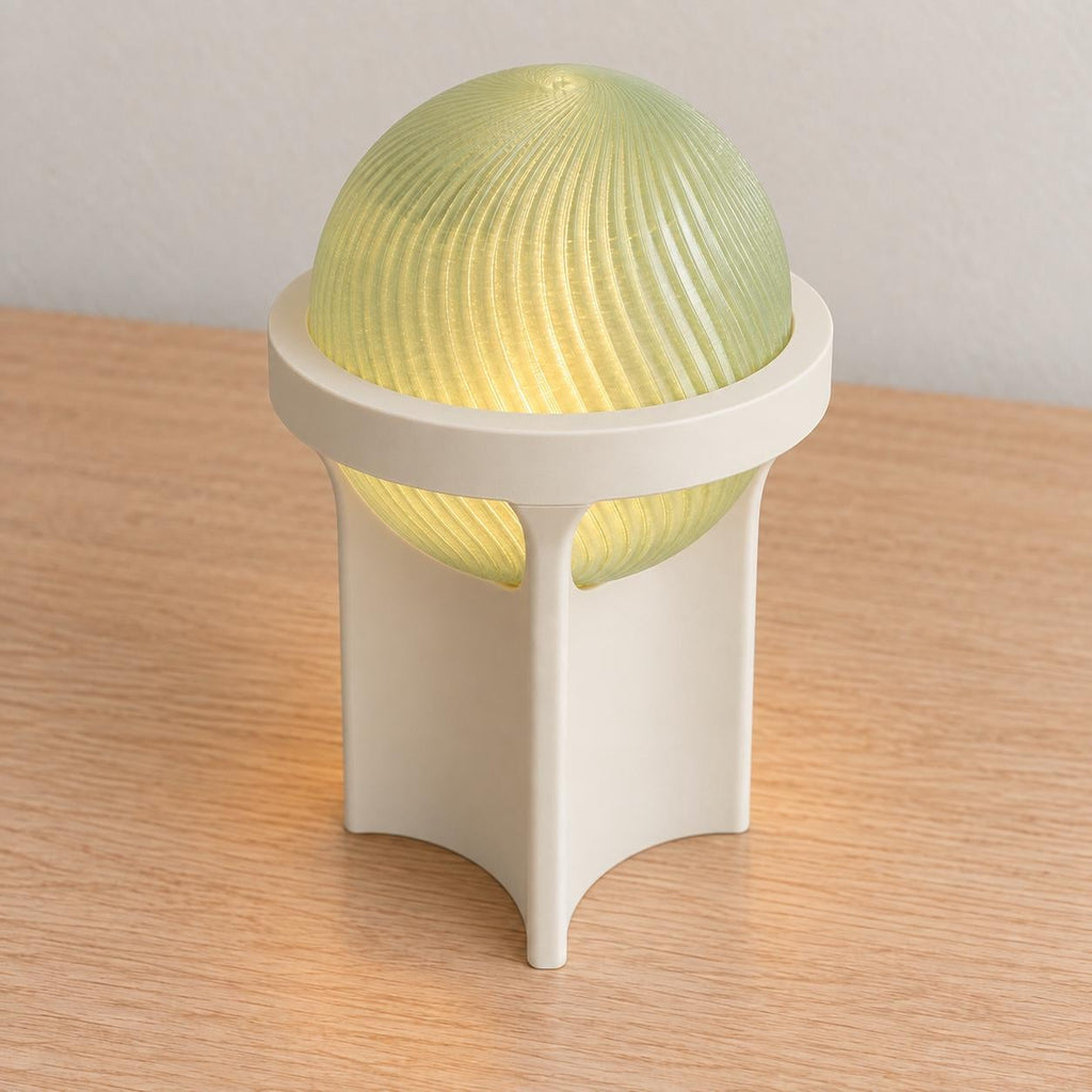 Elevated view of the Sage Pearl Orbessa lamp with an Ivory White base and ring, showing the closed spiral top of its glowing Light Jade globe.