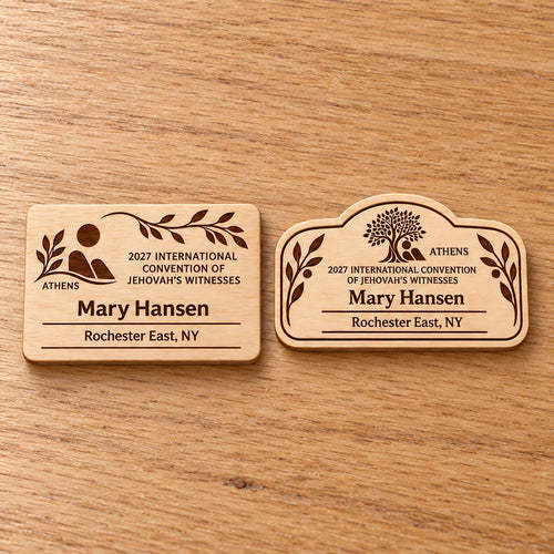 Two Athens mini natural-birch engraved badge designs, slot-free and laid separately on a light oak tabletop; each shows sample personalization.