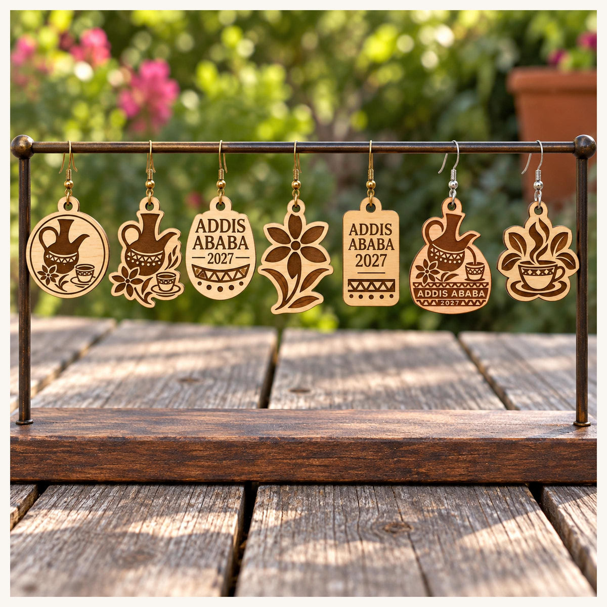 One earring from each selected Addis Ababa 2027 birch design on a wooden display stand outdoors.