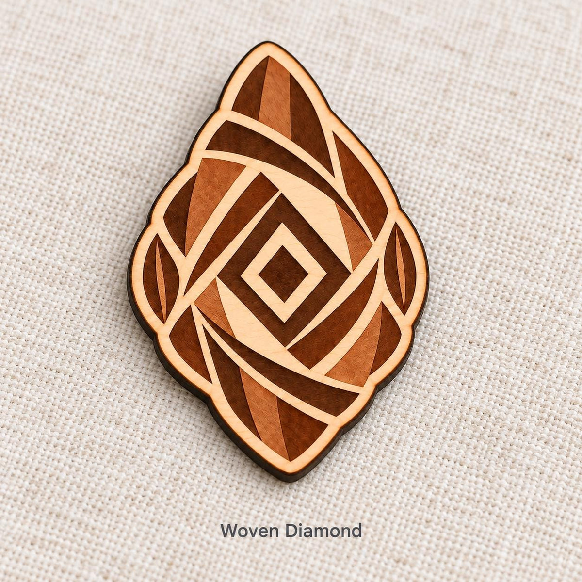 Close-up of Accra Woven Diamond engraved birch pin on linen, with design name caption.