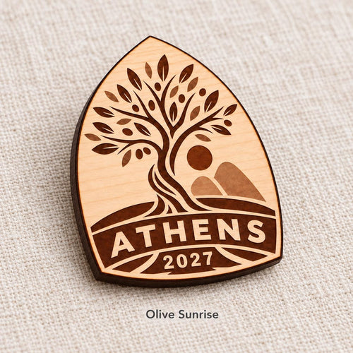 Close-up of Athens Olive Sunrise engraved birch pin on linen, with design name caption.