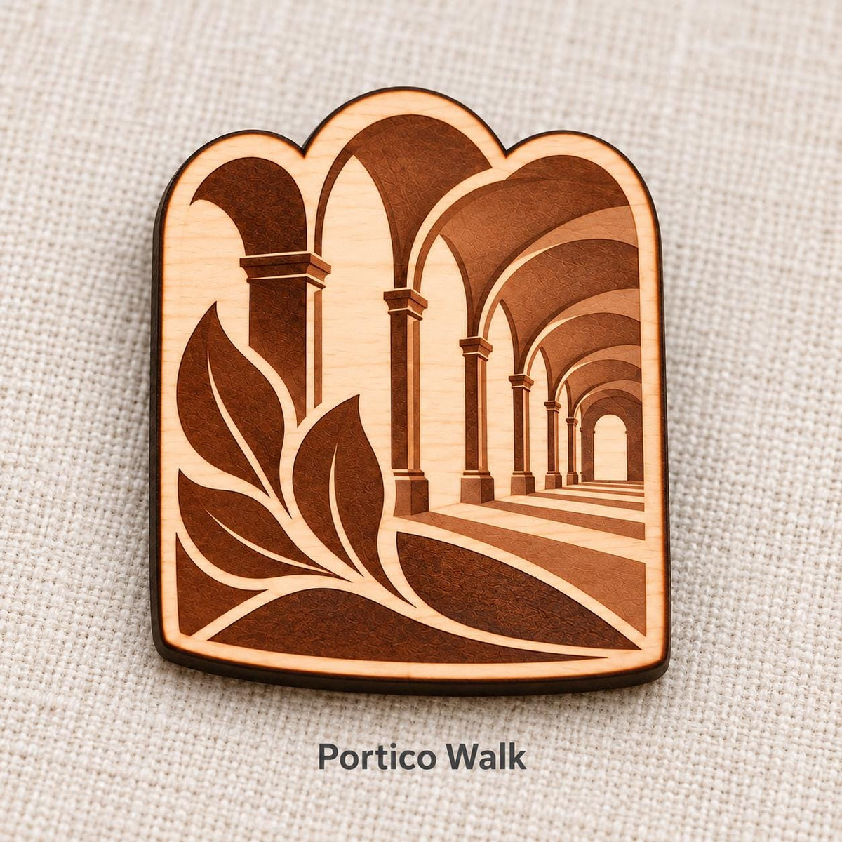 Close-up of Bologna Portico Walk engraved birch pin on linen, with design name caption.