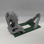 Stone gray dinosaur skull on a hunter green rocker switch plate, angled view.