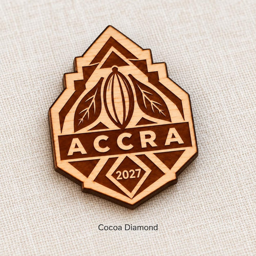 Close-up of Accra Cocoa Diamond engraved birch pin on linen, with design name caption.