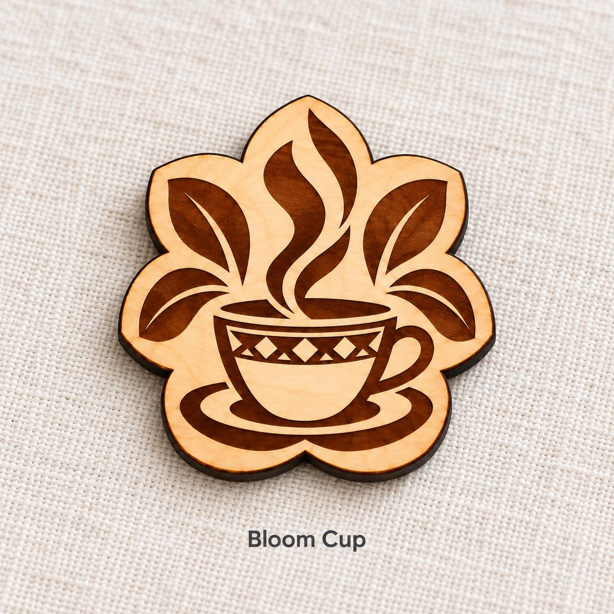 Close-up of Addis Ababa Bloom Cup engraved birch pin on linen, with design name caption.