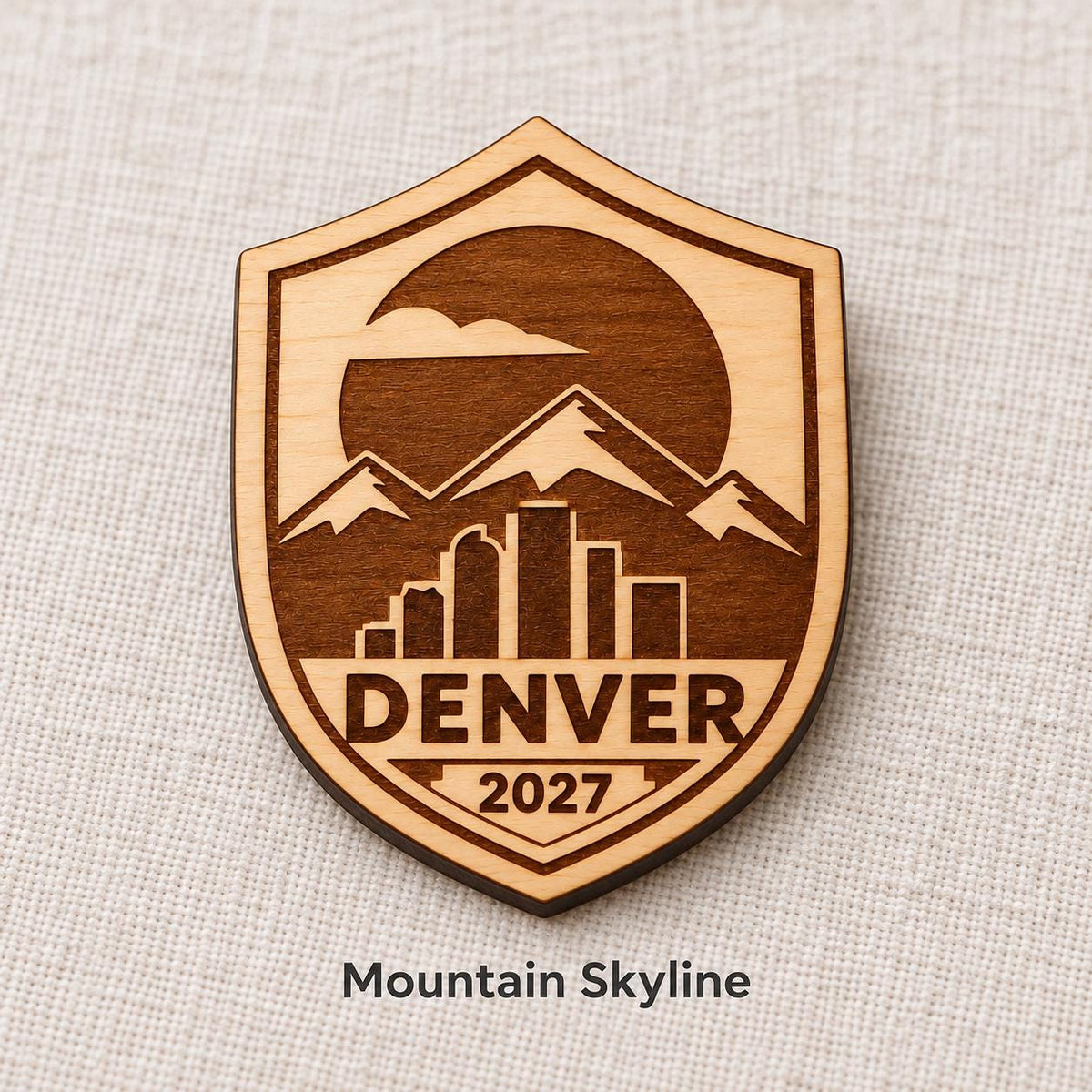 Close-up of Denver Mountain Skyline engraved birch pin on linen, with design name caption.