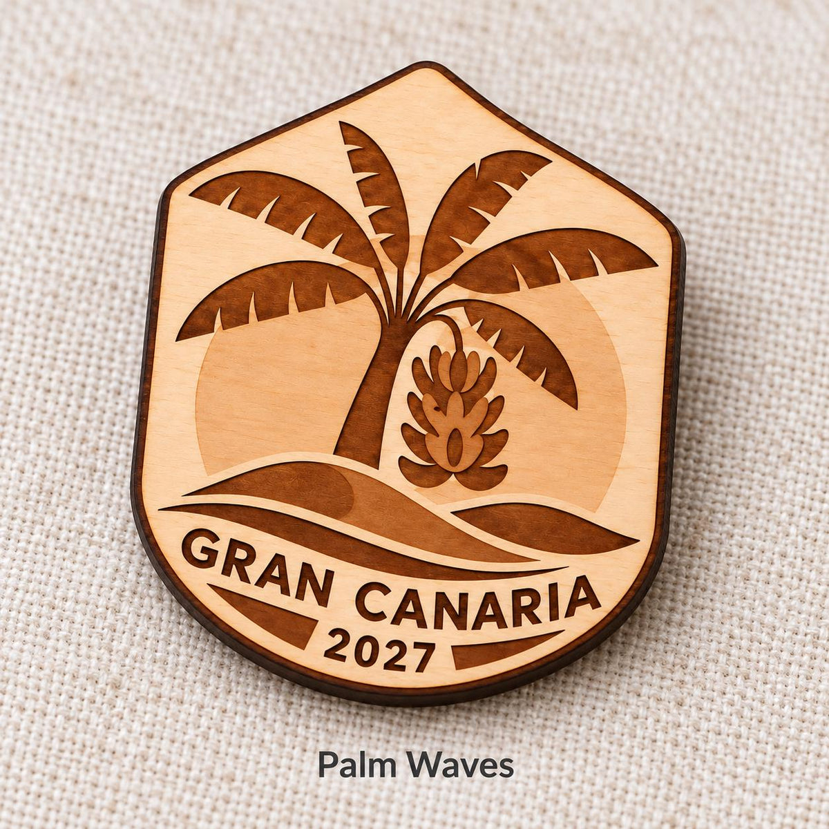 Close-up of Gran Canaria Palm Waves engraved birch pin on linen, with design name caption.