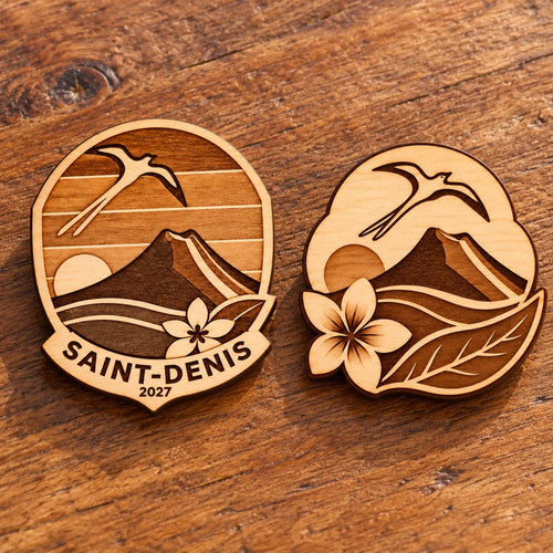 Two Saint-Denis engraved birch convention pin designs lying face-up on a wooden table in natural light.