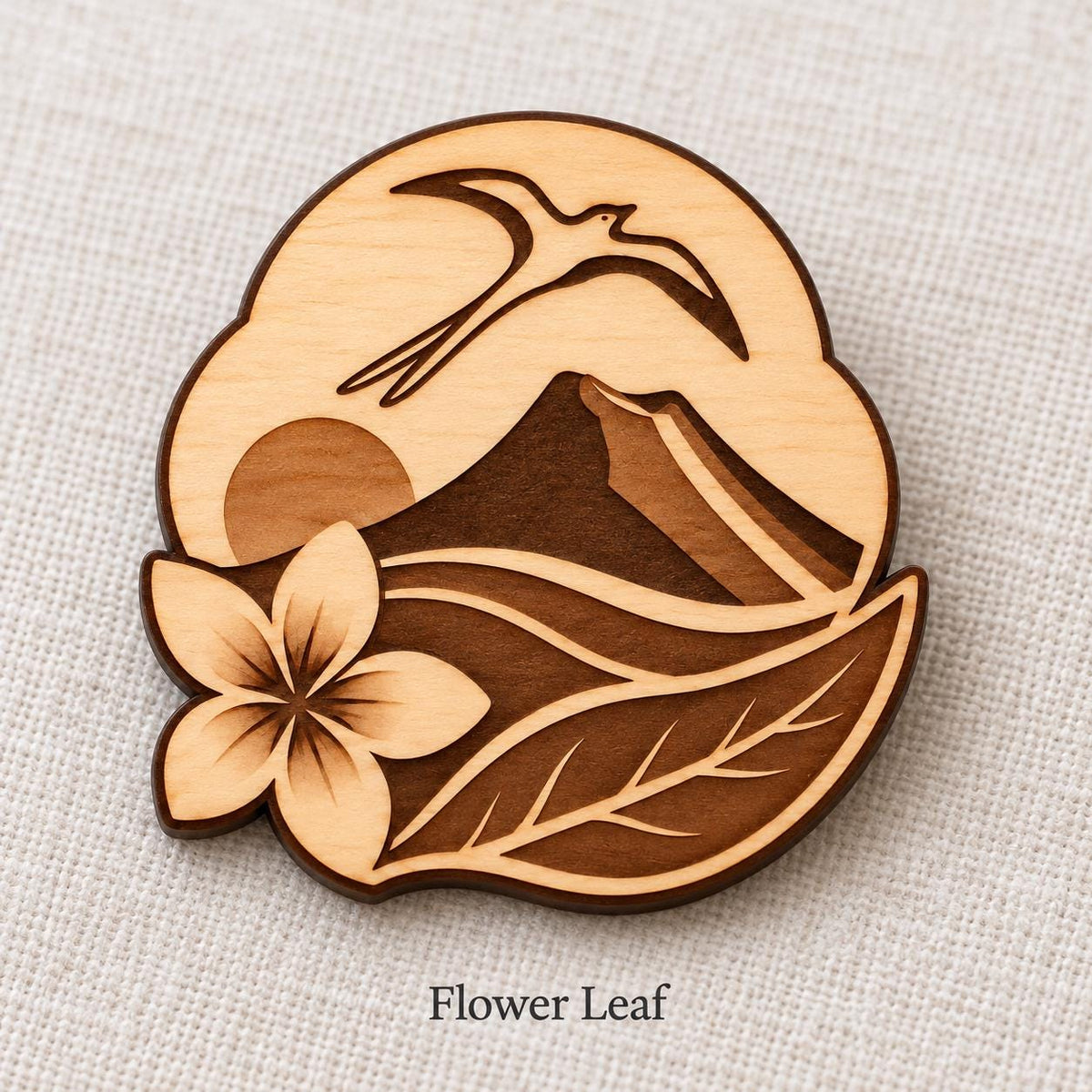 Close-up of Saint-Denis Flower Leaf engraved birch pin on linen, with design name caption.