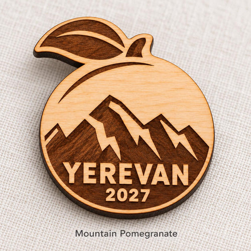 Close-up of Yerevan Mountain Pomegranate engraved birch pin on linen, with design name caption.