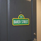 Green and yellow street-style sign reading Baker Street and 123 on a dark door.
