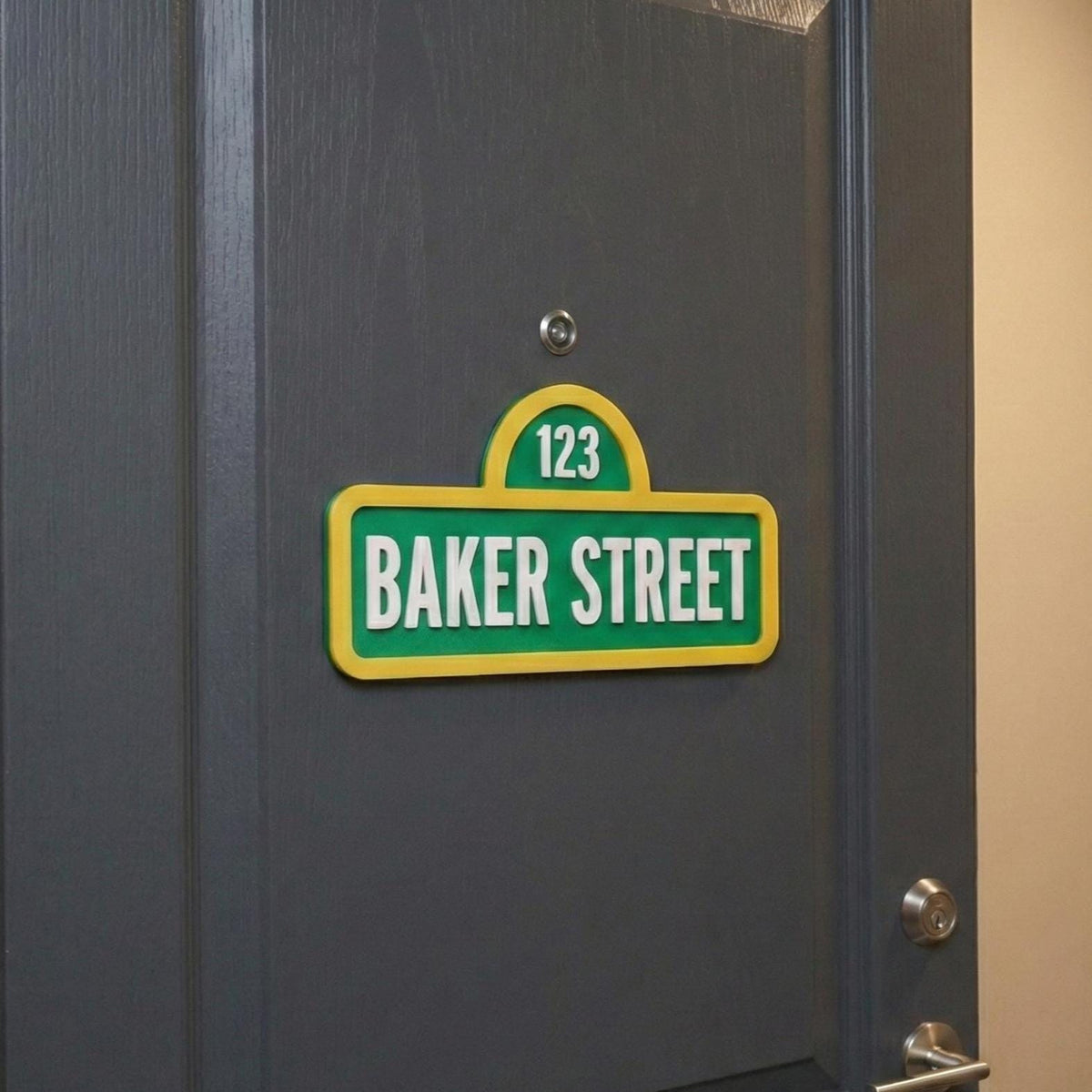 Green and yellow street-style sign reading Baker Street and 123 on a dark door.