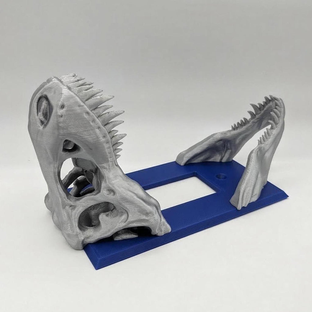 Silver dinosaur skull on a navy blue rocker switch plate, angled view.