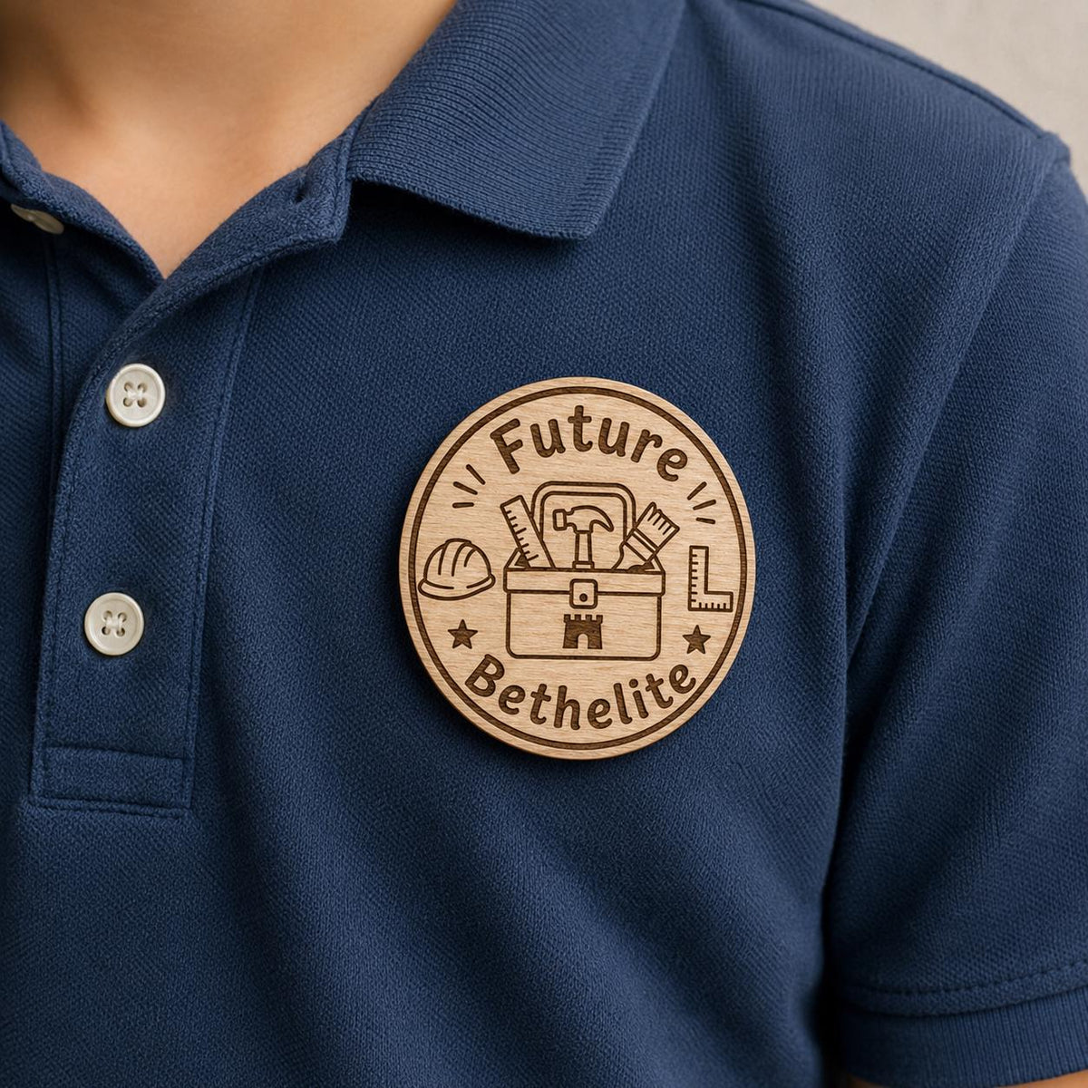 Close-up of the Future Bethelite natural birch engraved accessory attached to fabric, showing its dark artwork and shaped edge.